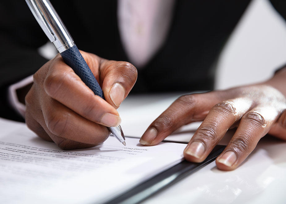 Close up of hands signing a paper with a pen